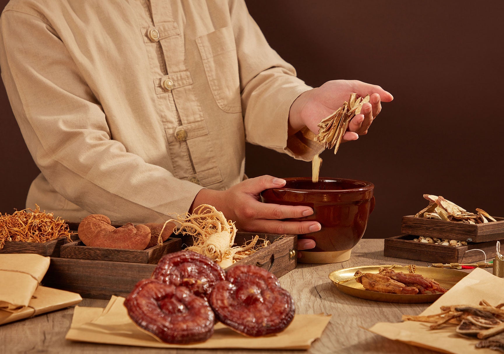 A person is pouring food into a bowl, with visible pieces of dried mushrooms nearby on the table.