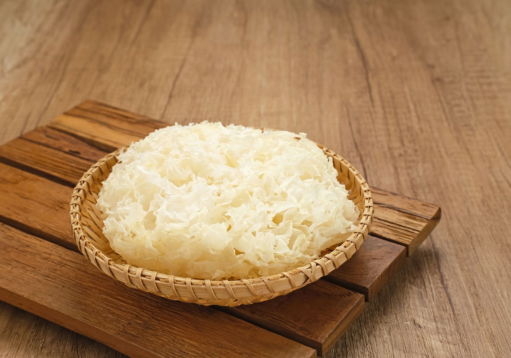 A bowl of steamed white rice sits on a wooden table, showcasing its fluffy texture and simplicity, perfect for various culinary uses.