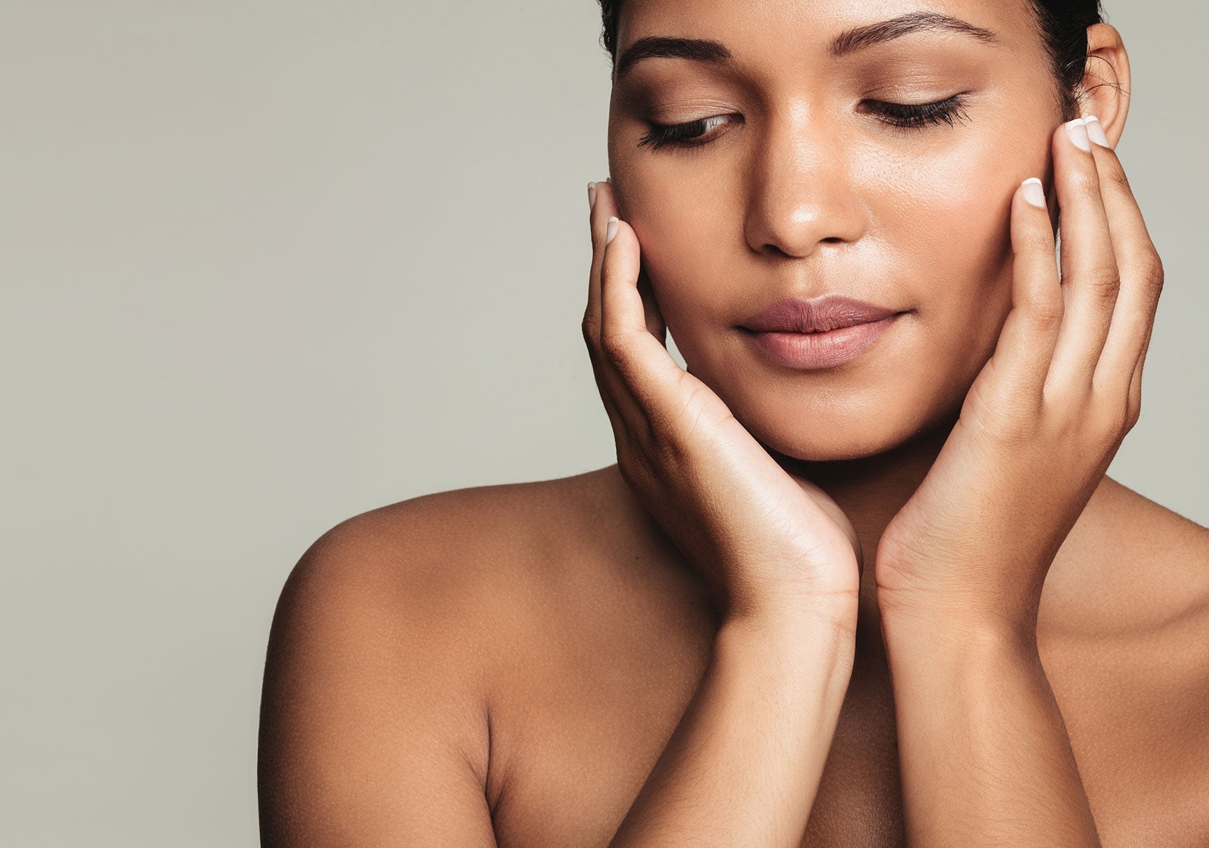 A close-up of a woman gently touching her face, highlighting her lips, nose, and eyes with a focus on facial features and skin texture.