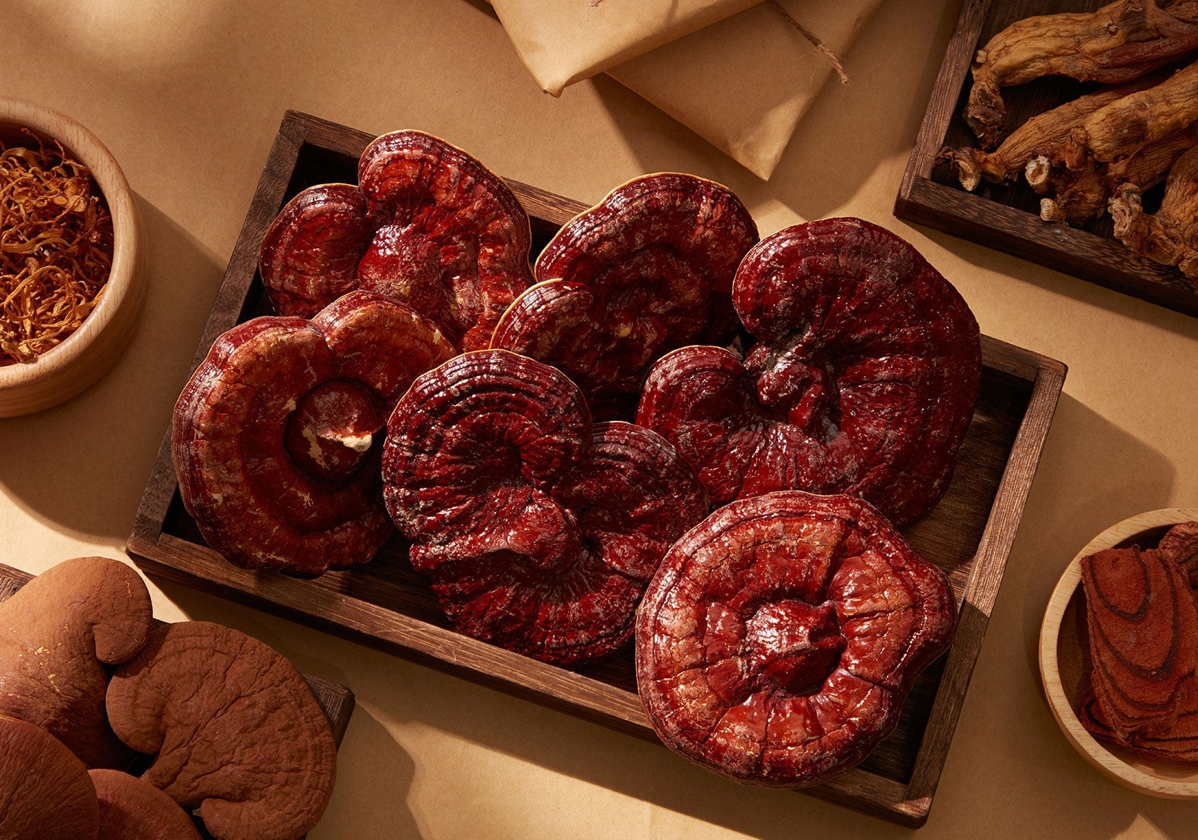 A group of brown mushrooms in a wooden box, with nearby dried mushrooms and a piece of cake on a wooden plate.