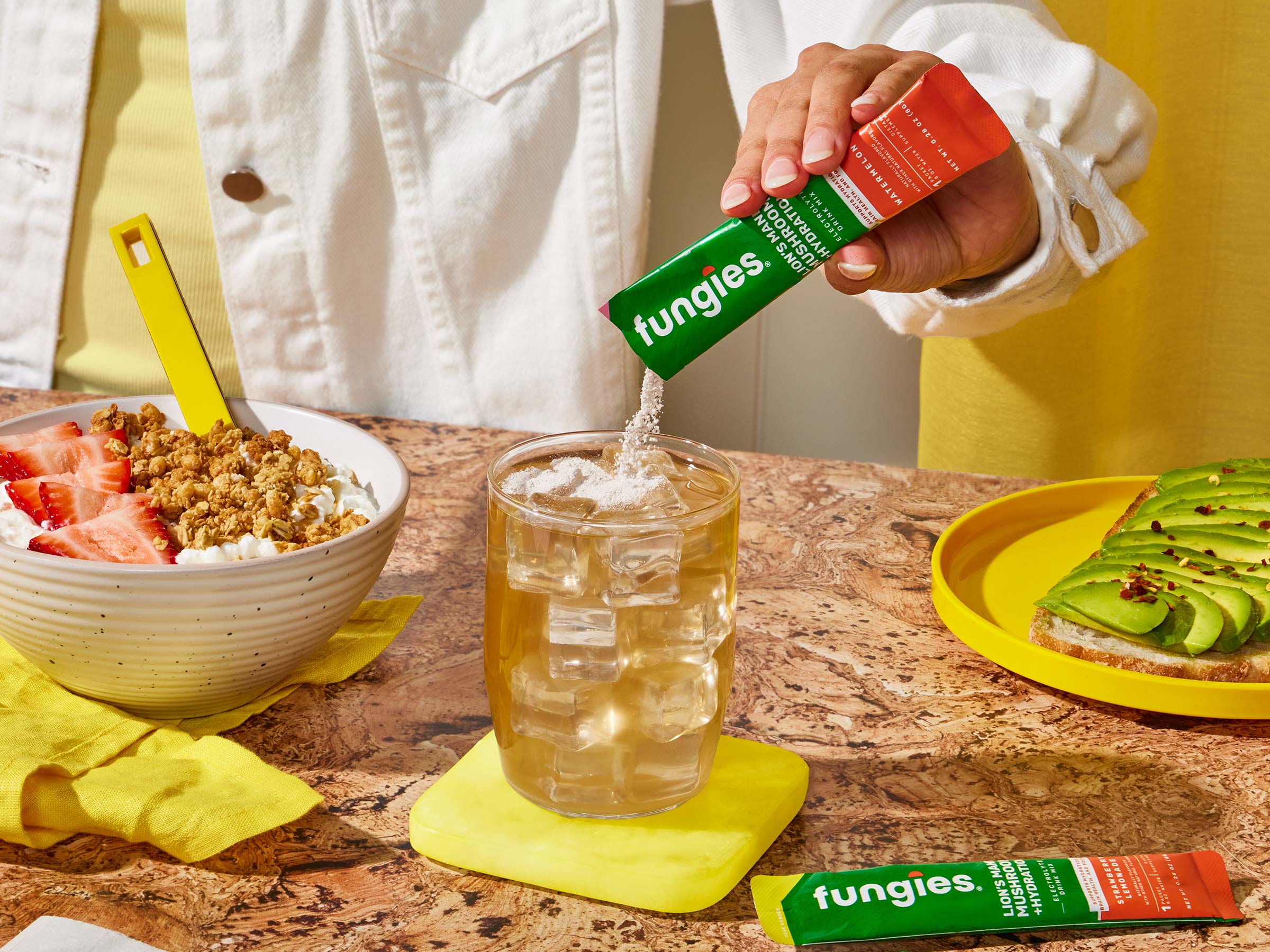 A woman mixing Fungies Lion's Mane + Hydration drink mix with her morning water and breakfast for a healthy day ahead