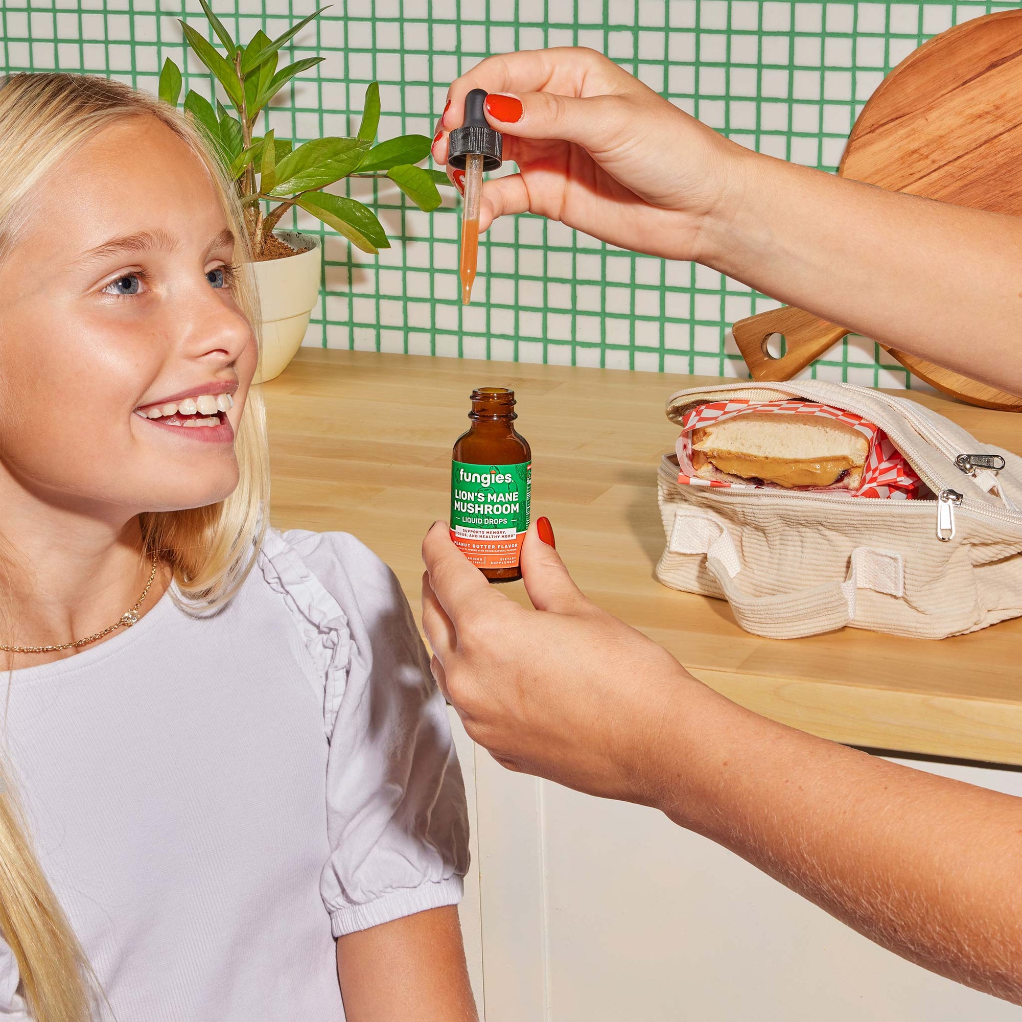 Lion's Mane Mushroom Liquid Drops with a green label held by a smiling girl, designed to boost brain health, focus, and memory.