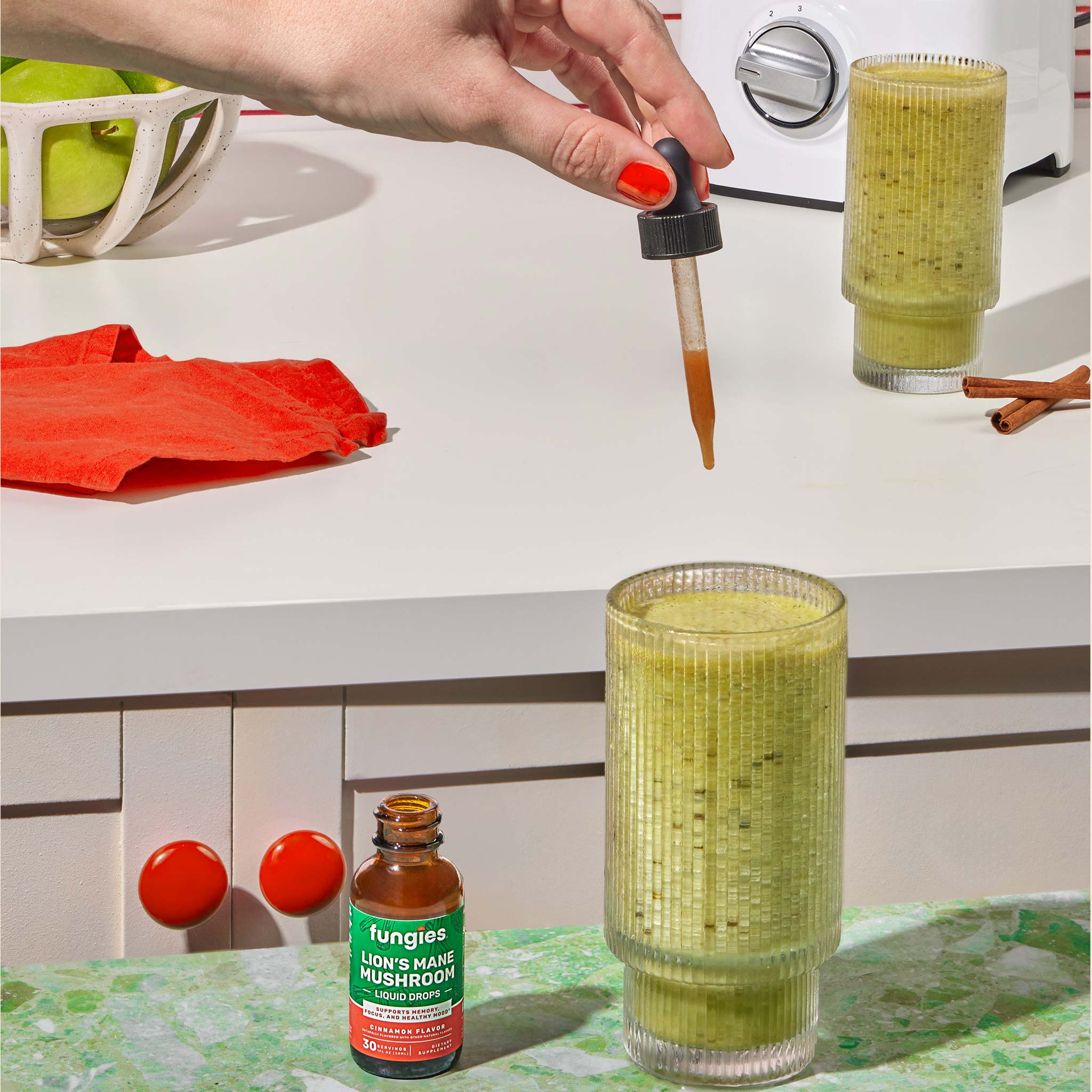 Lion's Mane Mushroom Liquid Drops held over a green smoothie, highlighting their use as a brain health supplement for focus and clarity enhancement.