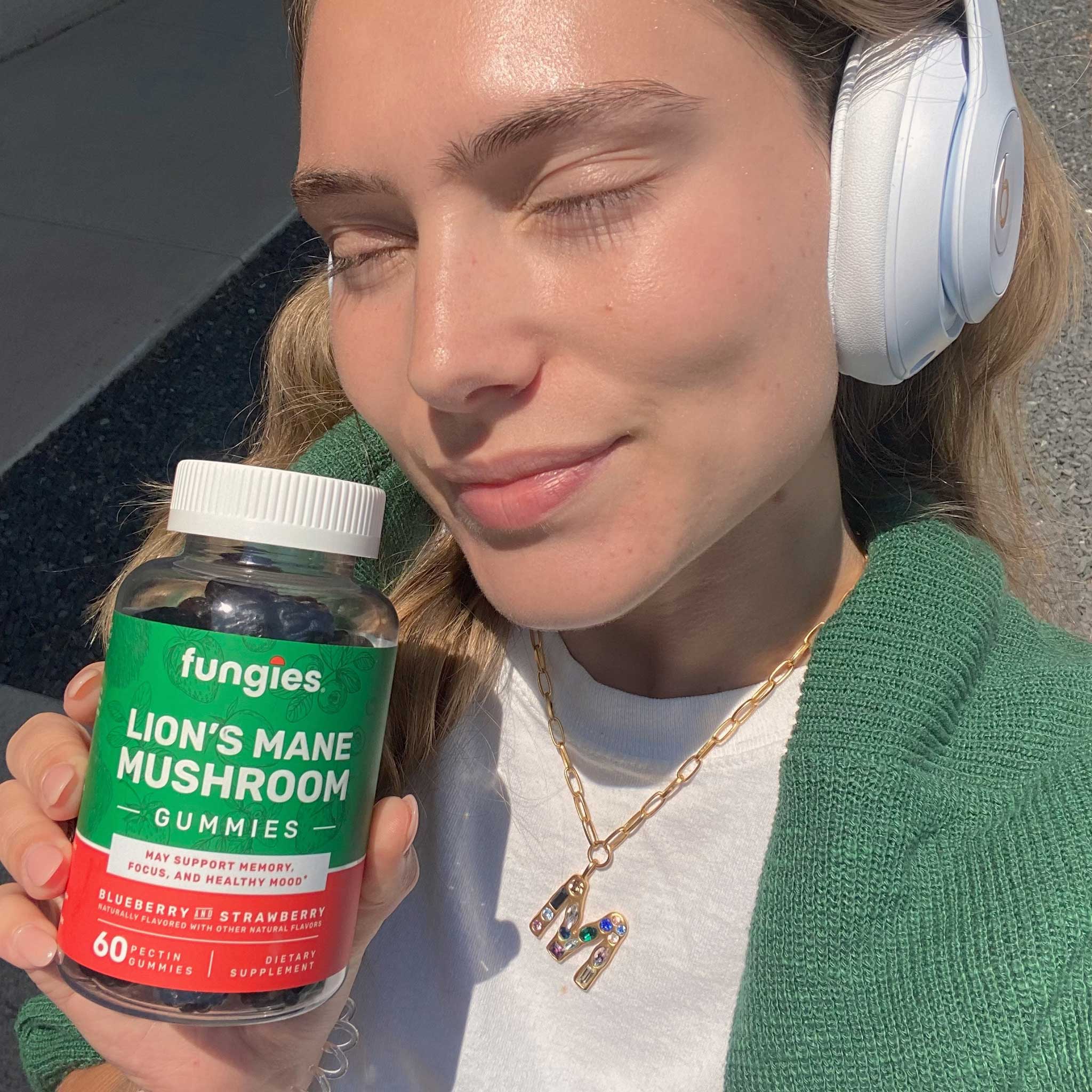 Young happy woman holding her lion's mane mushroom gummies