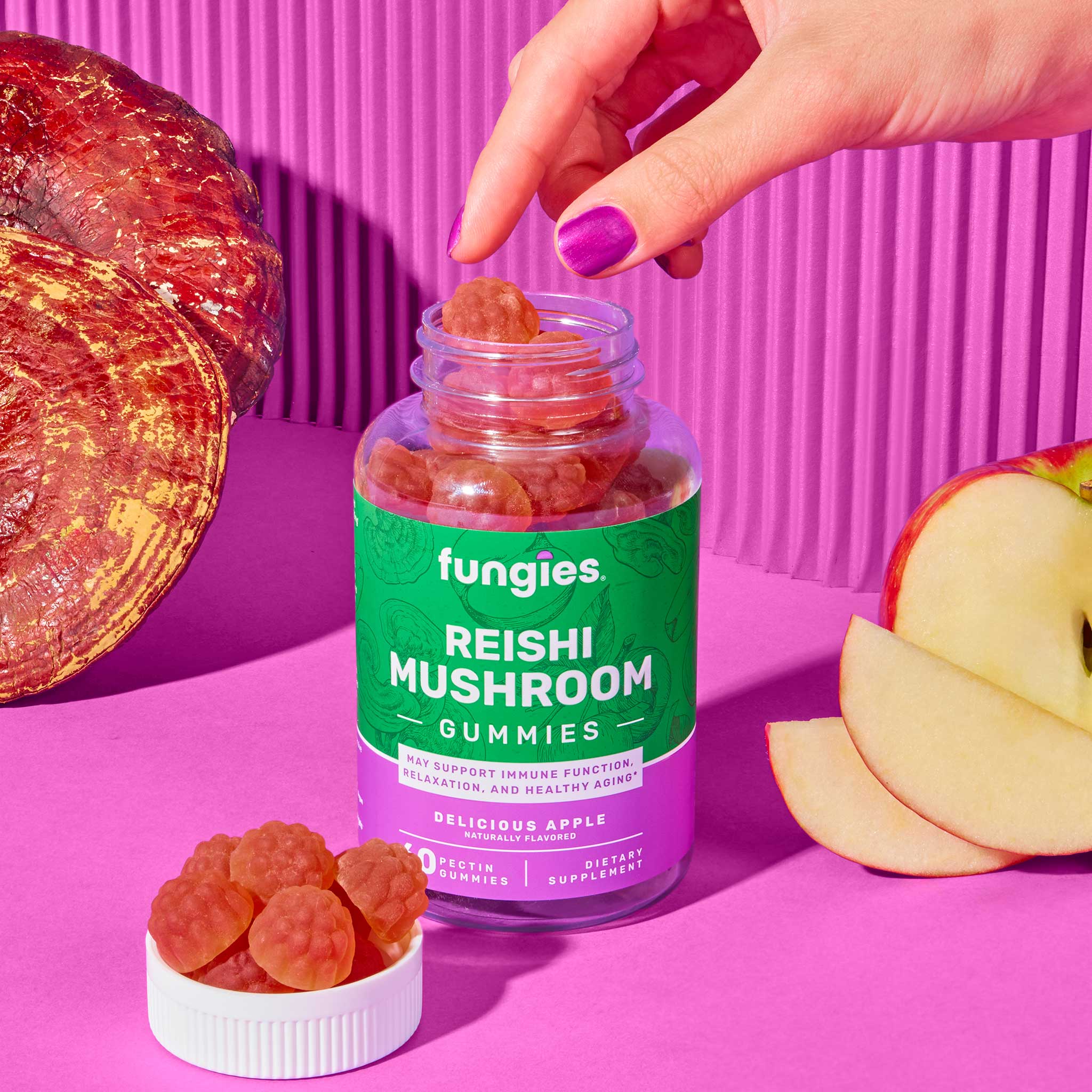 Hand reaching for a jar labeled Reishi Mushroom Gummies (60 Count), next to a bowl of gummies, emphasizing their apple flavor and wellness benefits.