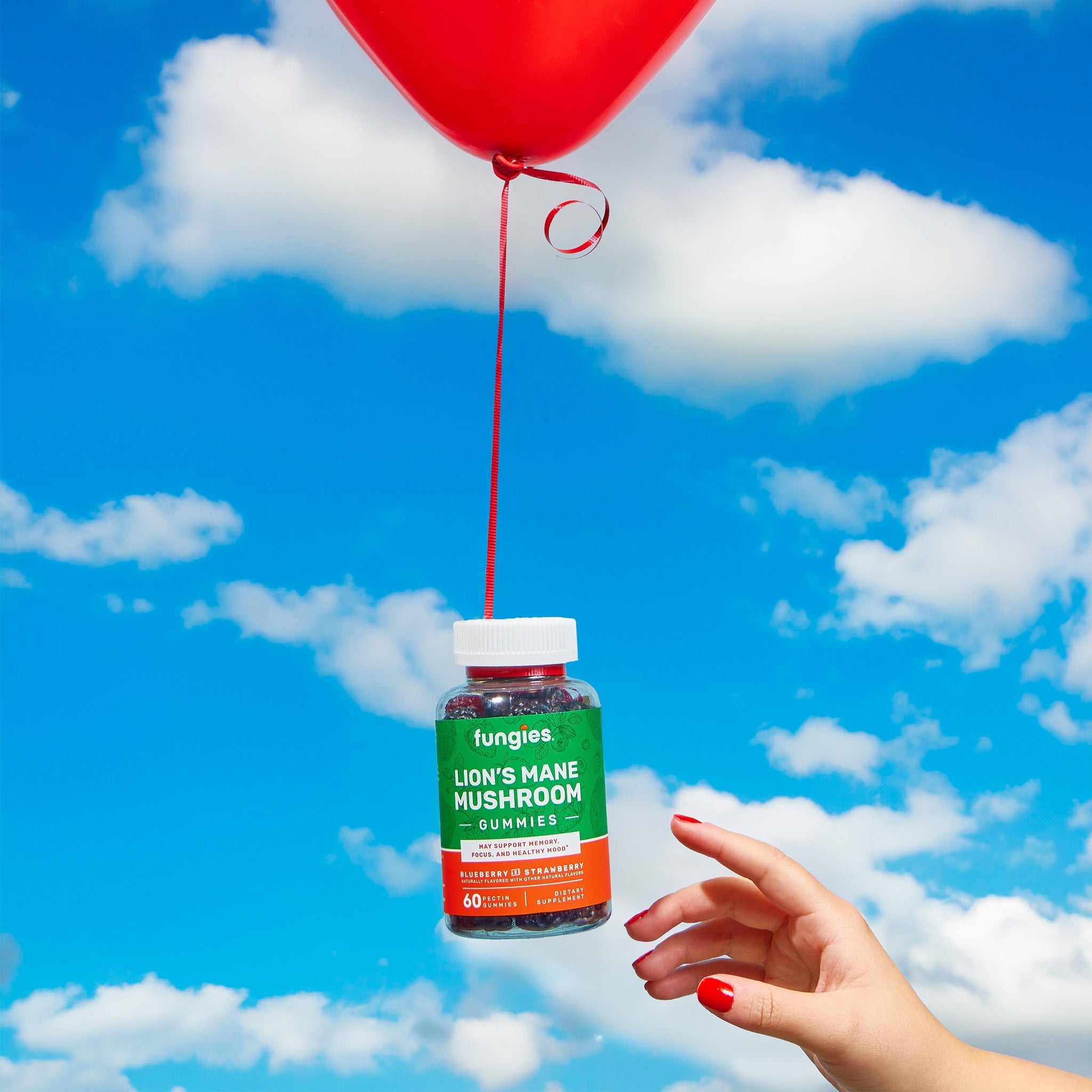 Hand holding red balloon and a jar of Mushroom Gummy Bundle, showcasing Lion's Mane, Cordyceps, Reishi, and Tremella gummies for diverse health benefits.