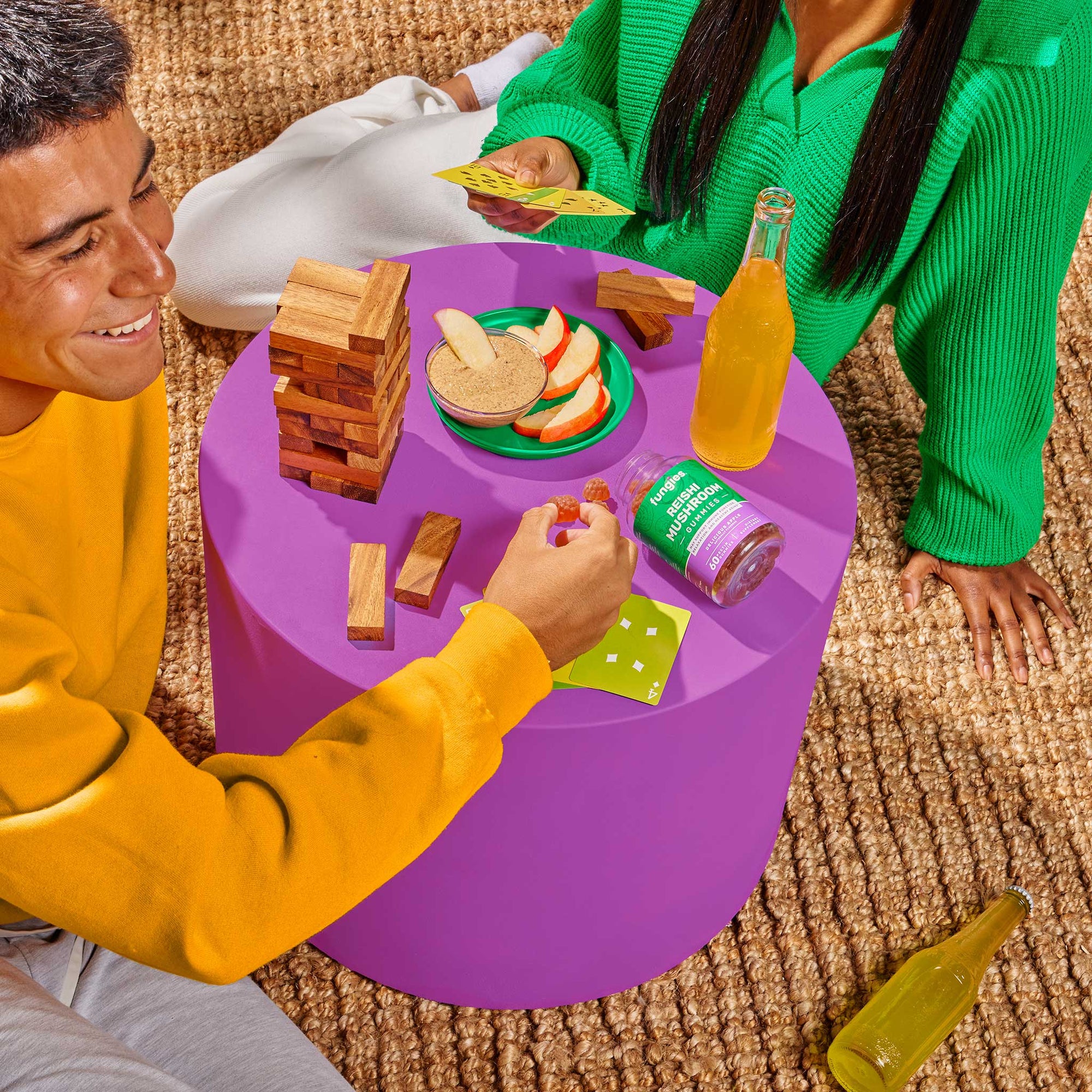 Friends playing Jenga and eating snacks while relaxing with Fungies Reishi Mushroom Gummies